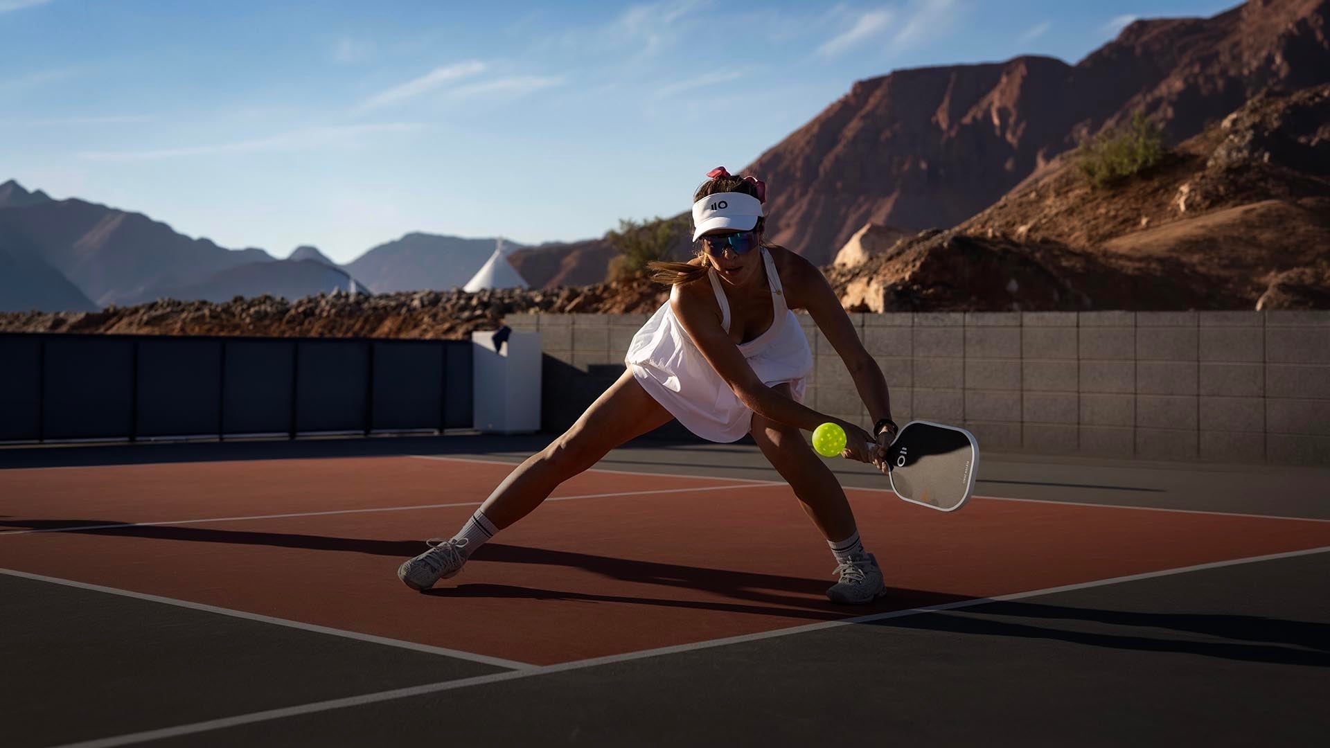 Eleven Zero Sports pickleball paddles in black carbon and Kevlar resting on a blue pickleball court surface.