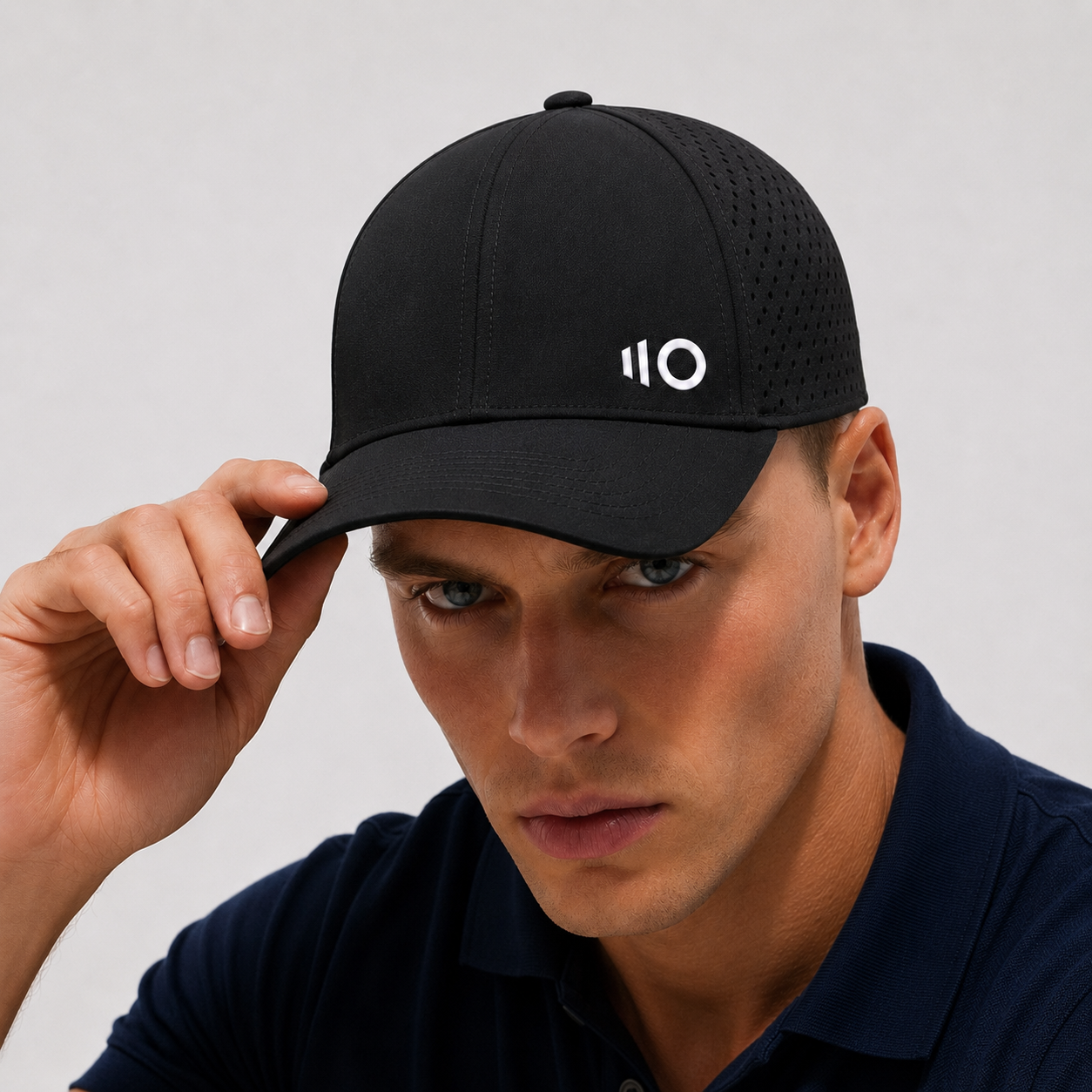 Man wearing a black cap with a logo on a gray background