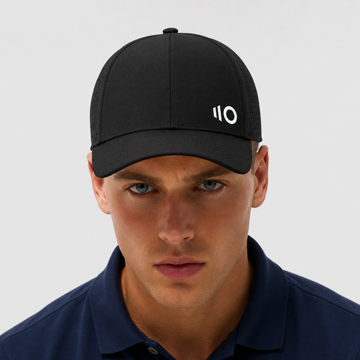 Woman wearing a black cap with a logo, smiling against a gray background