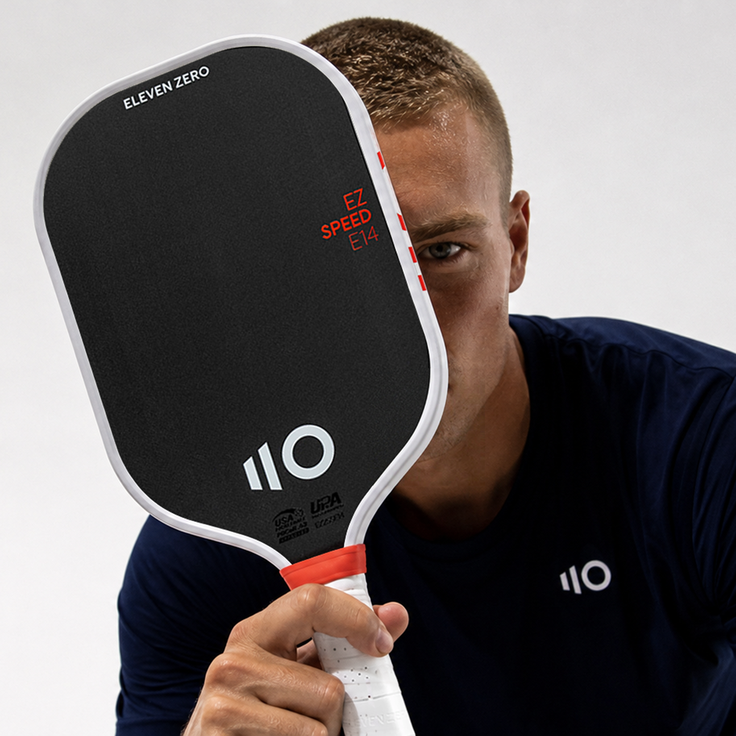 Sportive person holding the pickleball paddle with 'Eleven Zero' branding against a plain background