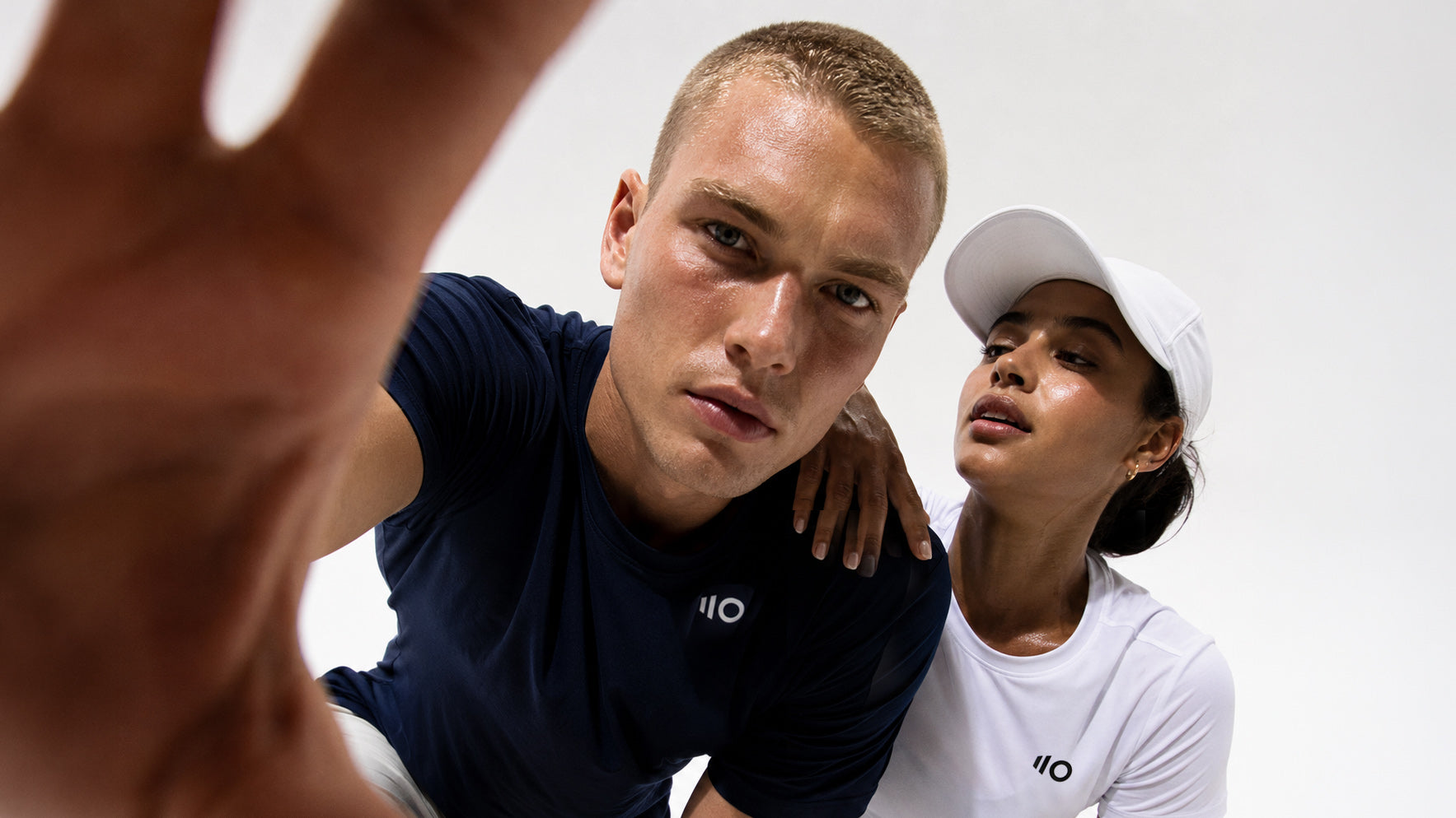 Two people wearing navy and white ELEVEN ZERO outfits with a brand logo on a plain background