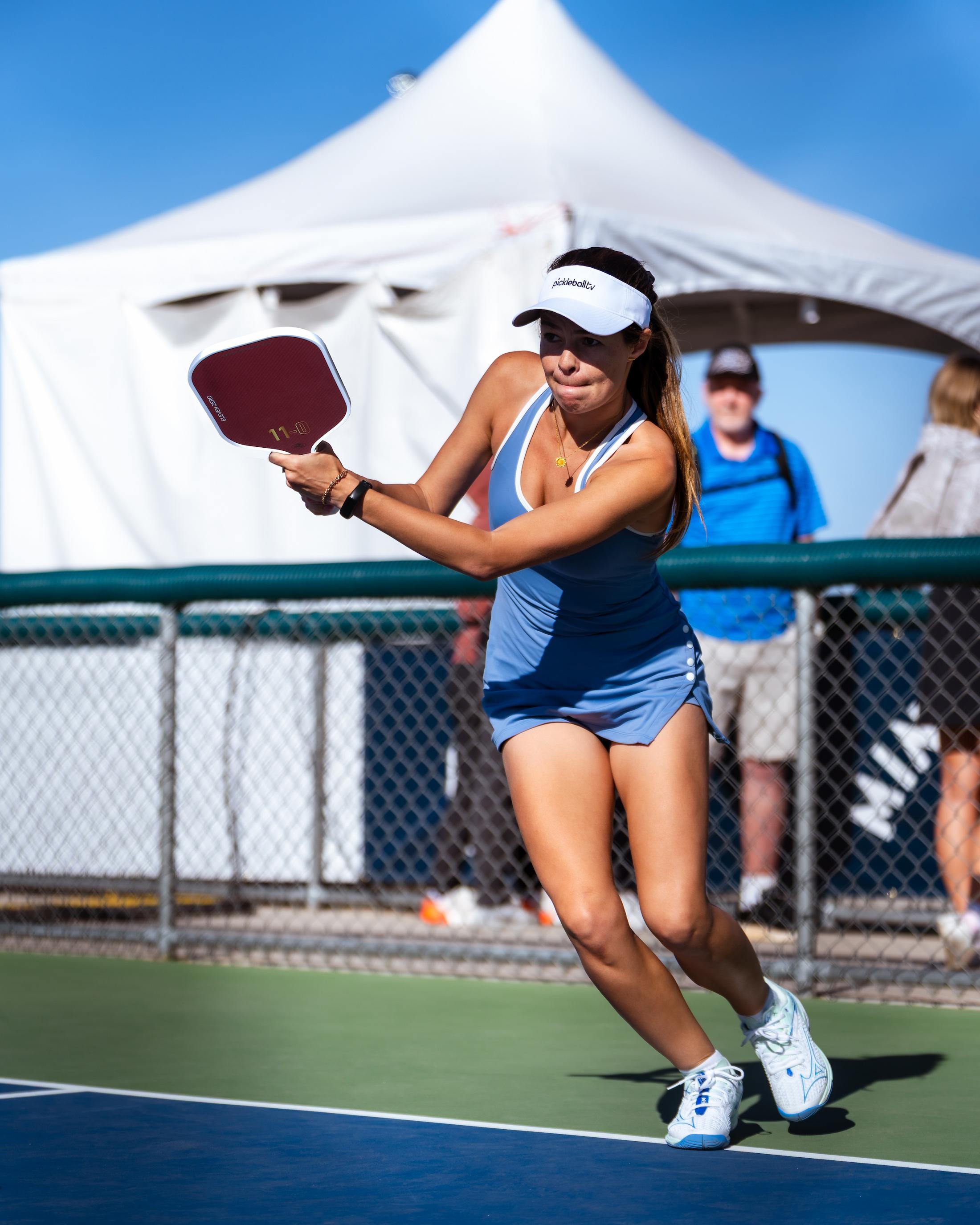 A female athlete playing pickleball with the Eleven Zero EZ Power Kevlar® paddle, focused and mid-action on an outdoor court.