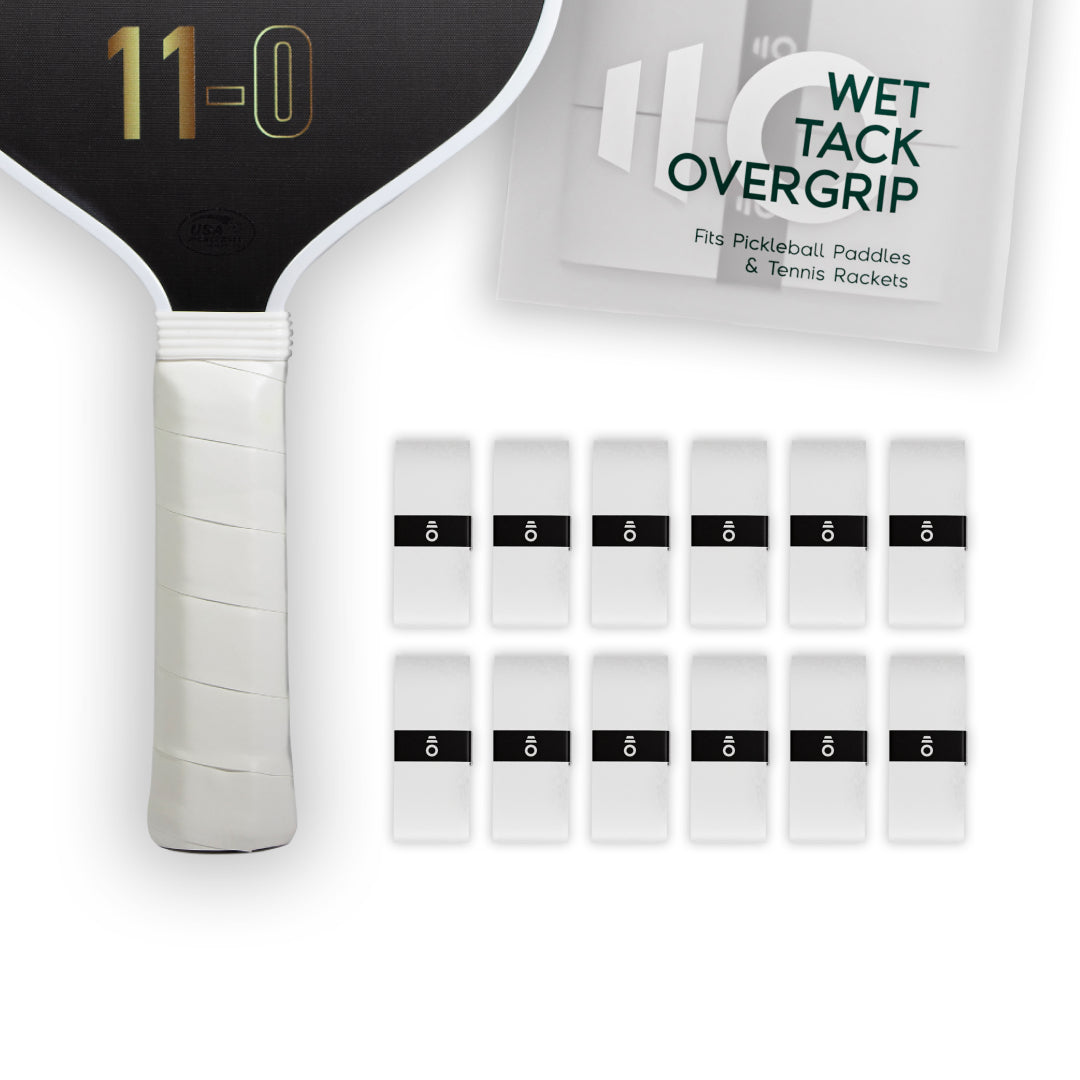 Twelve white Eleven Zero Wet Tack Overgrip strips neatly arranged beside the paddle handle and overgrip packaging.