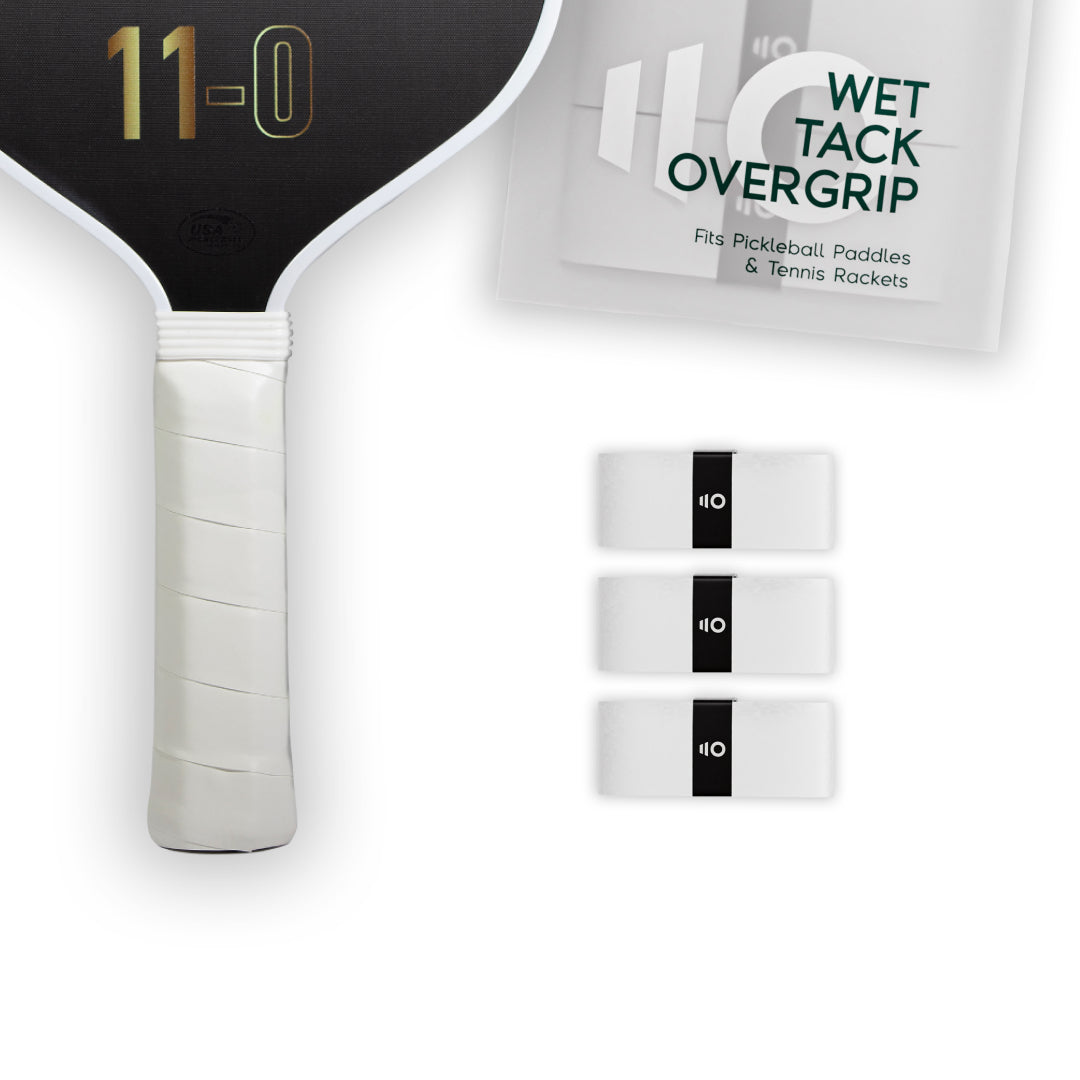 Three white Eleven Zero Wet Tack Overgrip strips lined up beside a pickleball paddle handle.