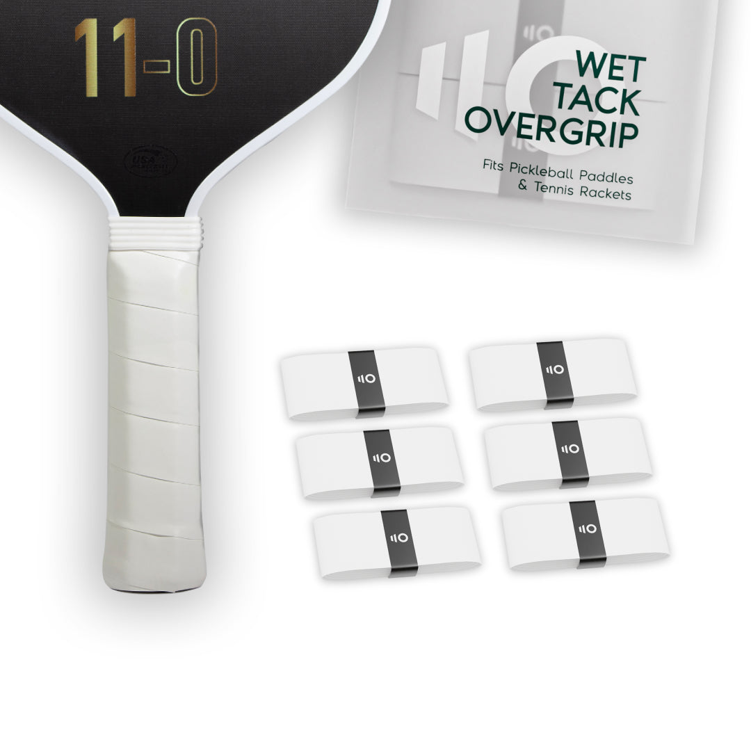 Six white Eleven Zero Wet Tack Overgrip strips displayed near the paddle handle and overgrip packaging.