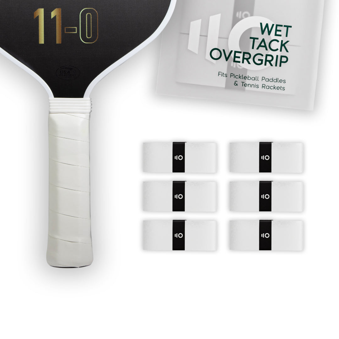Six white Eleven Zero Wet Tack Overgrip strips arranged next to a pickleball paddle handle and packaging.
