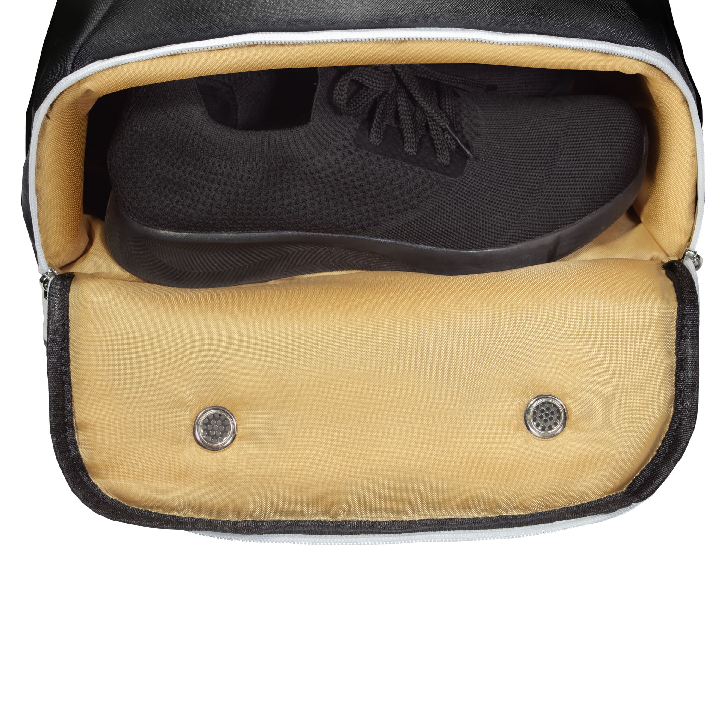 Bottom compartment of black Eleven Zero backpack open, showing ventilated shoe storage with a pair of black sneakers.