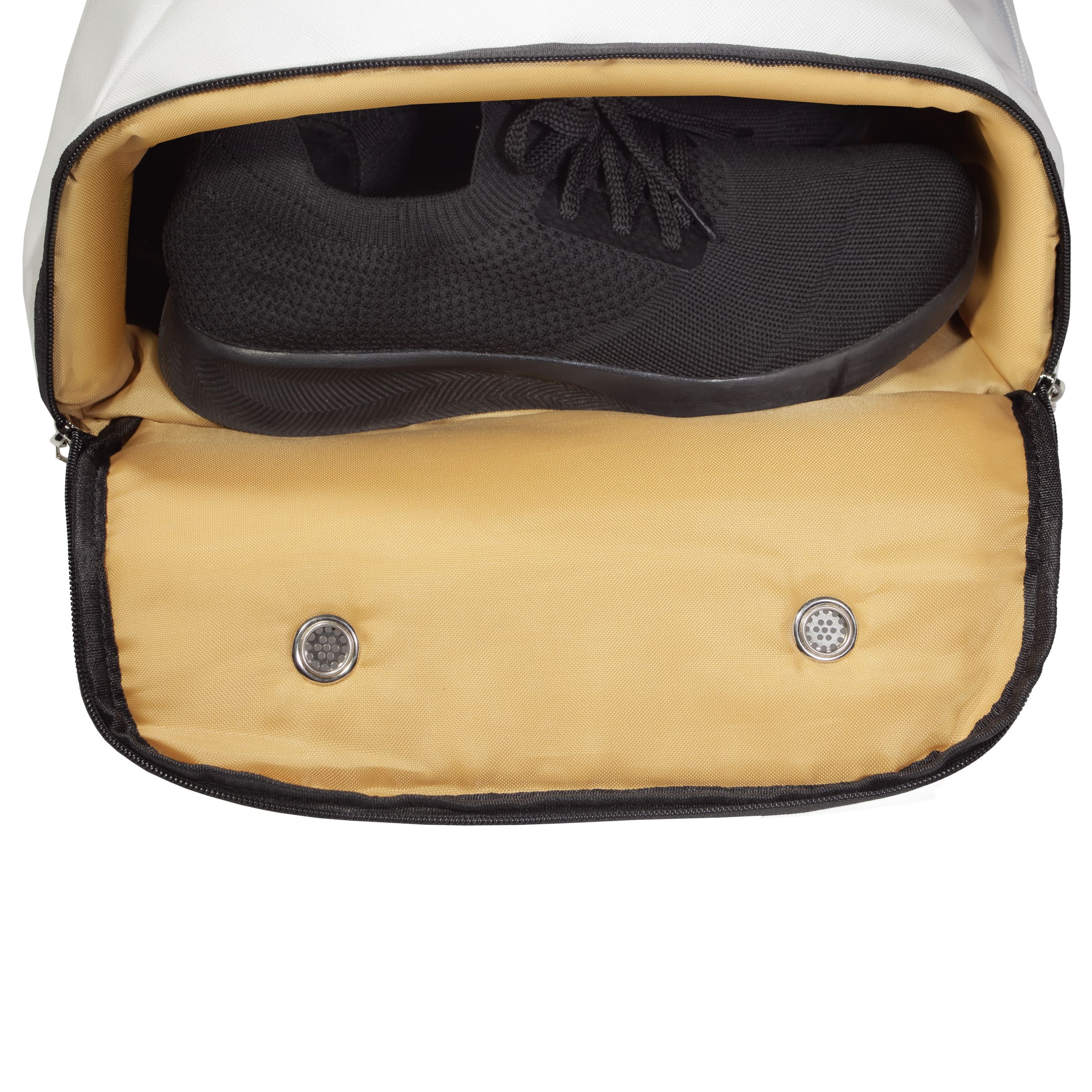Bottom shoe compartment of white Eleven Zero backpack with black sneakers inside and dual ventilation grommets.