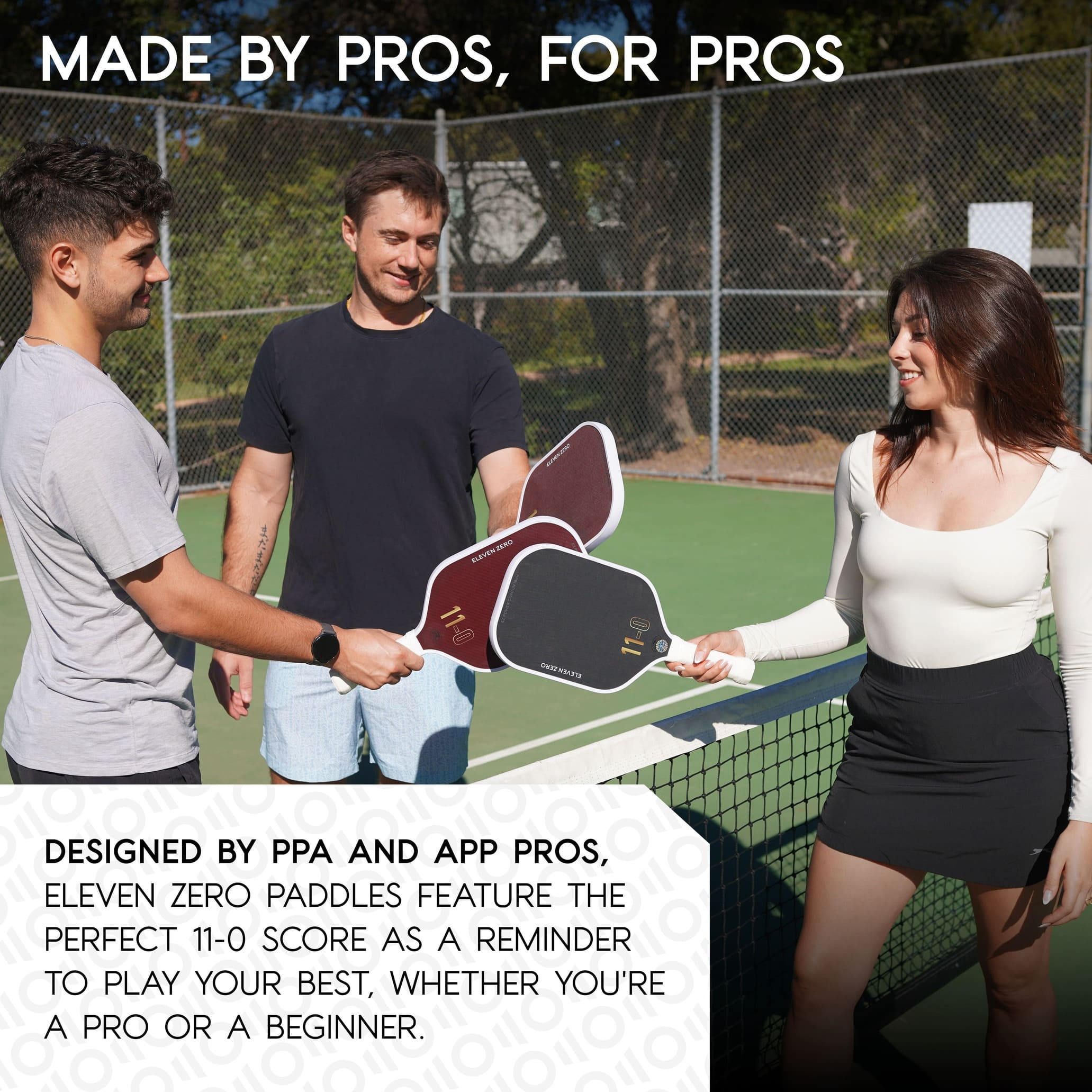 Three pickleball players smiling and touching Eleven Zero paddles—two maroon K-16 paddles and one black paddle—on a sunny outdoor pickleball court, illustrating paddles designed by professional players for both beginners and pros.