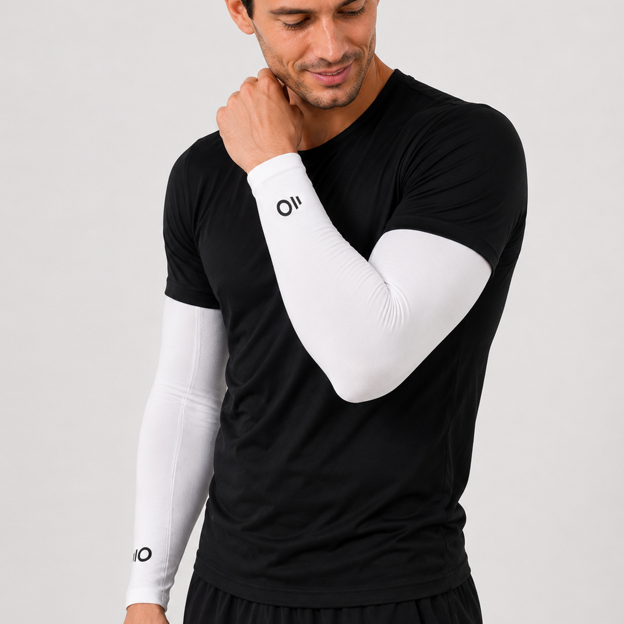Man wearing a black athletic shirt and white arm sleeves on a light gray background