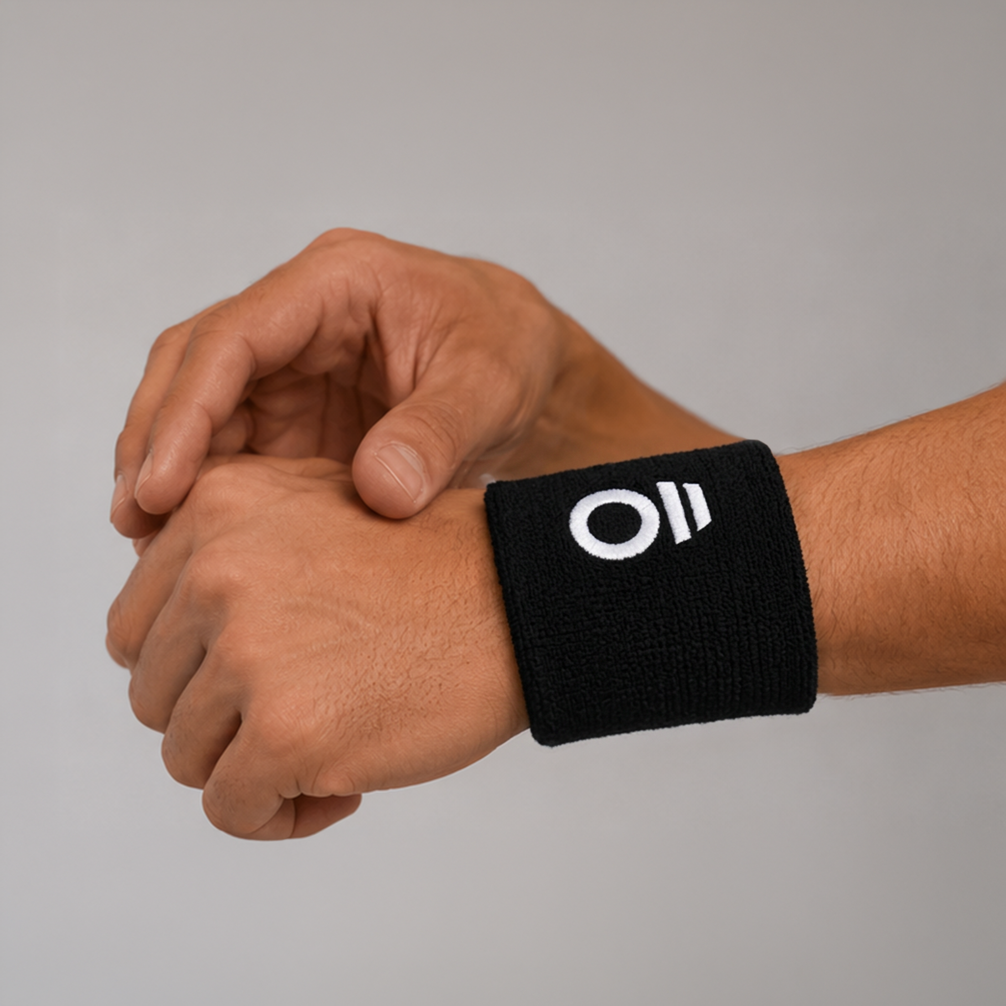 Black wristband with a white logo on a person's wrist against a gray background