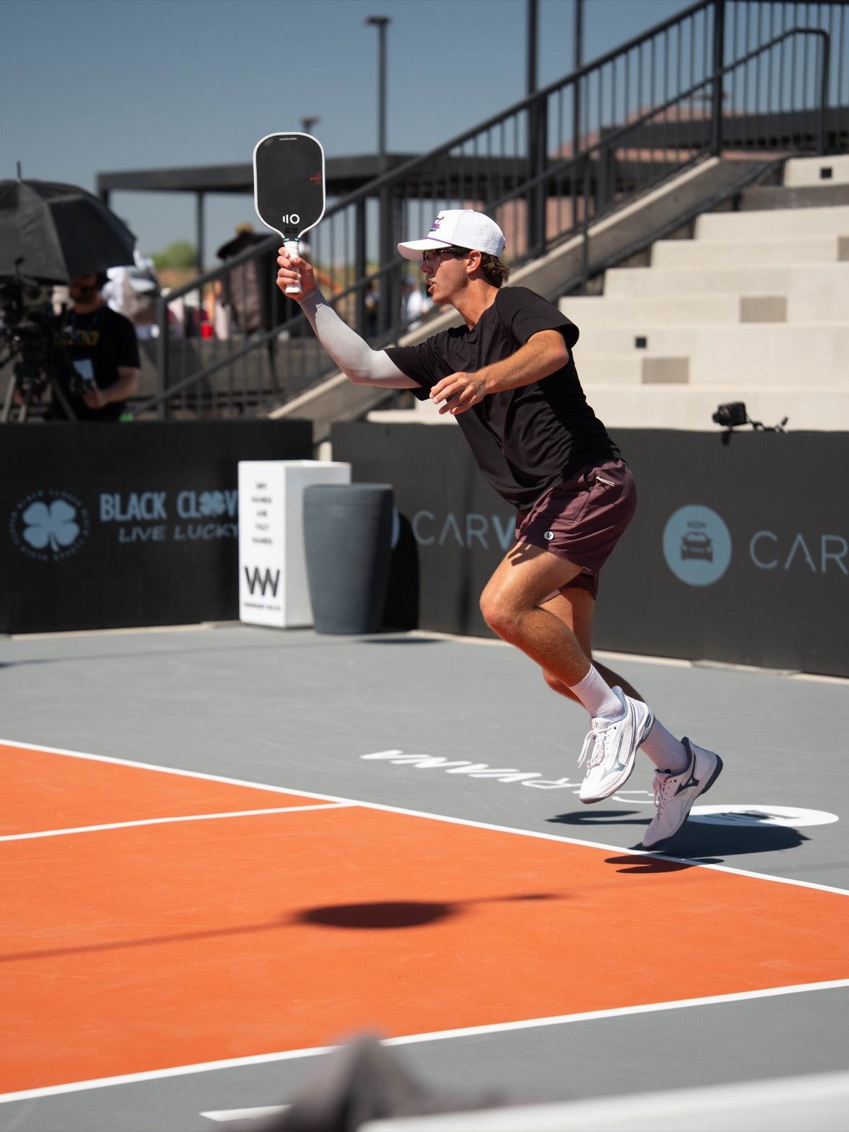 Pickleball player driving the ball mid-air on a tournament court