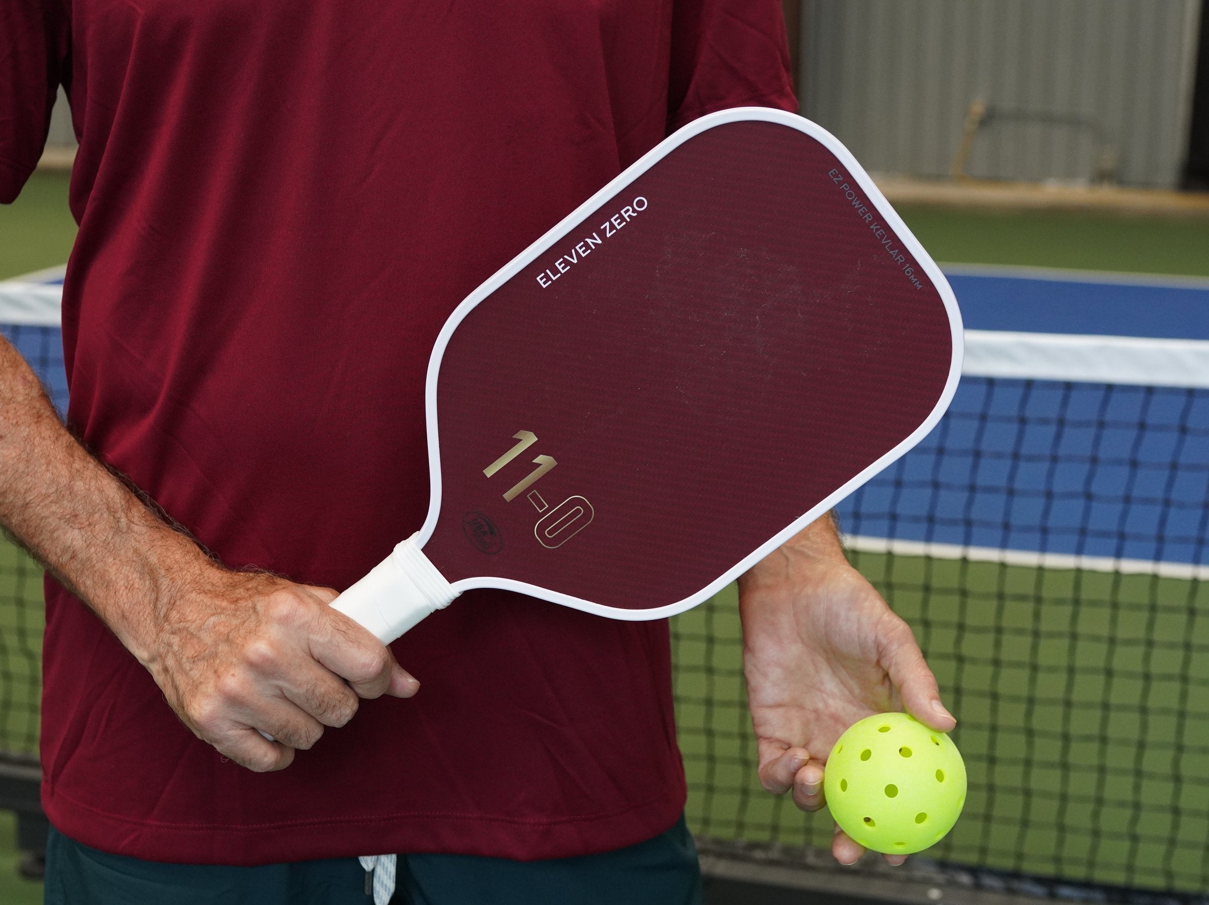 Player holding an Eleven Zero pickleball paddle on court - paddle weight guide