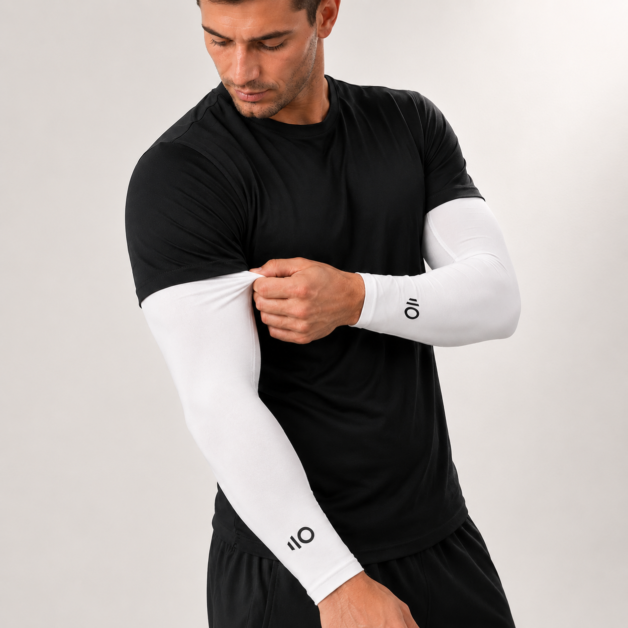 Man wearing a black athletic outfit with white Eleven Zero arm sleeves on a plain background