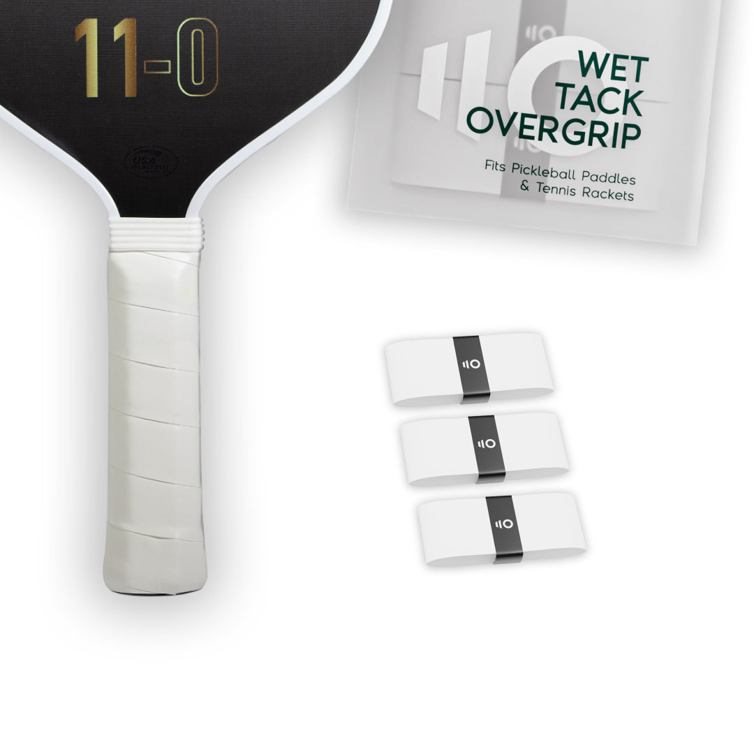 Three white Eleven Zero Wet Tack Overgrip strips shown beside the paddle handle and product packaging.