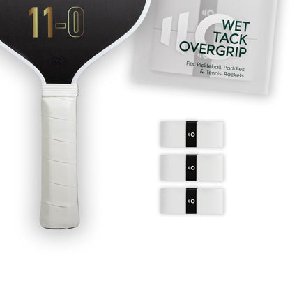 Three white Eleven Zero Wet Tack Overgrip strips lined up beside a pickleball paddle handle.