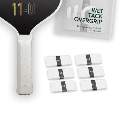 Six white Eleven Zero Wet Tack Overgrip strips displayed near the paddle handle and overgrip packaging.