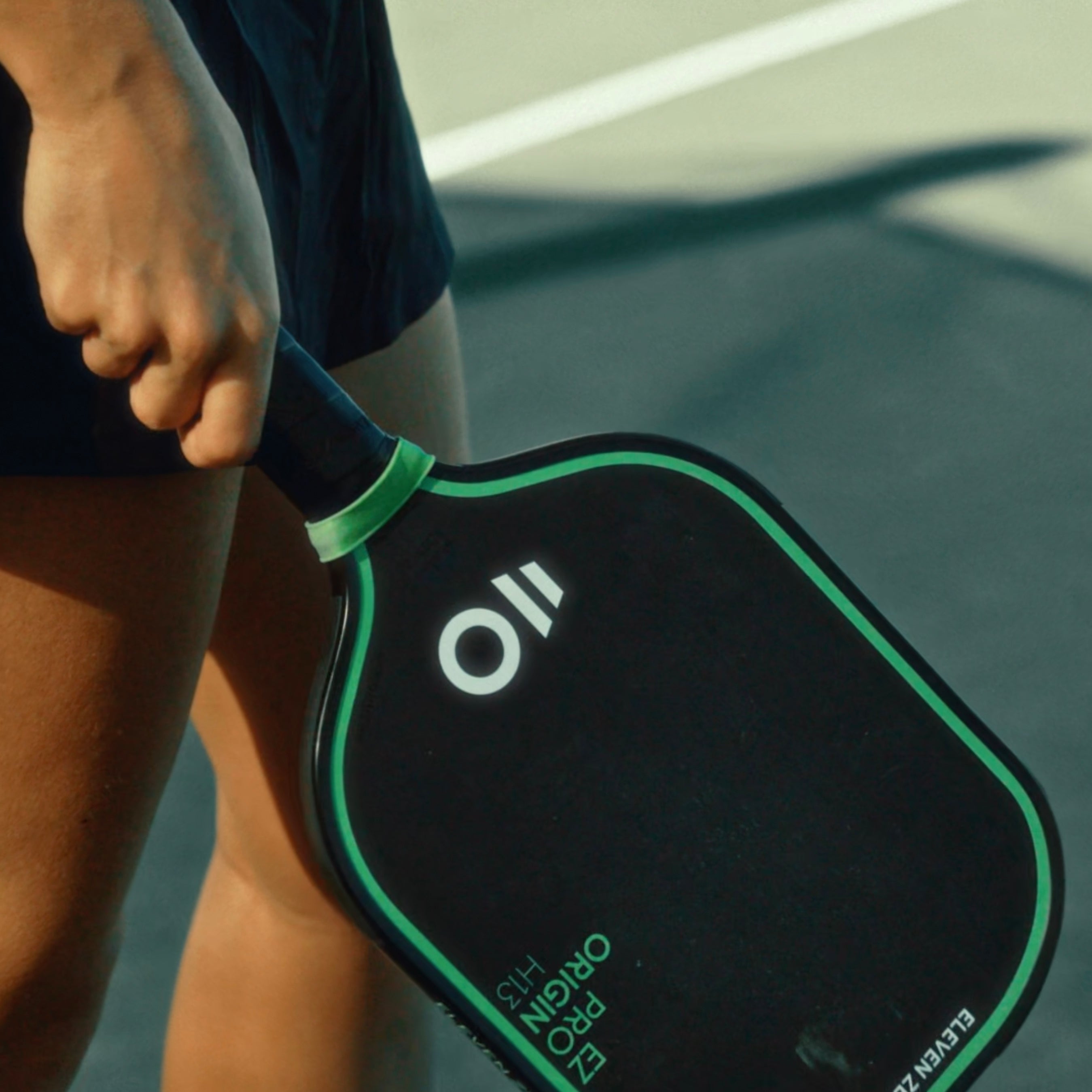 Player holding EZ Pro Origin H13 pickleball paddle on court
