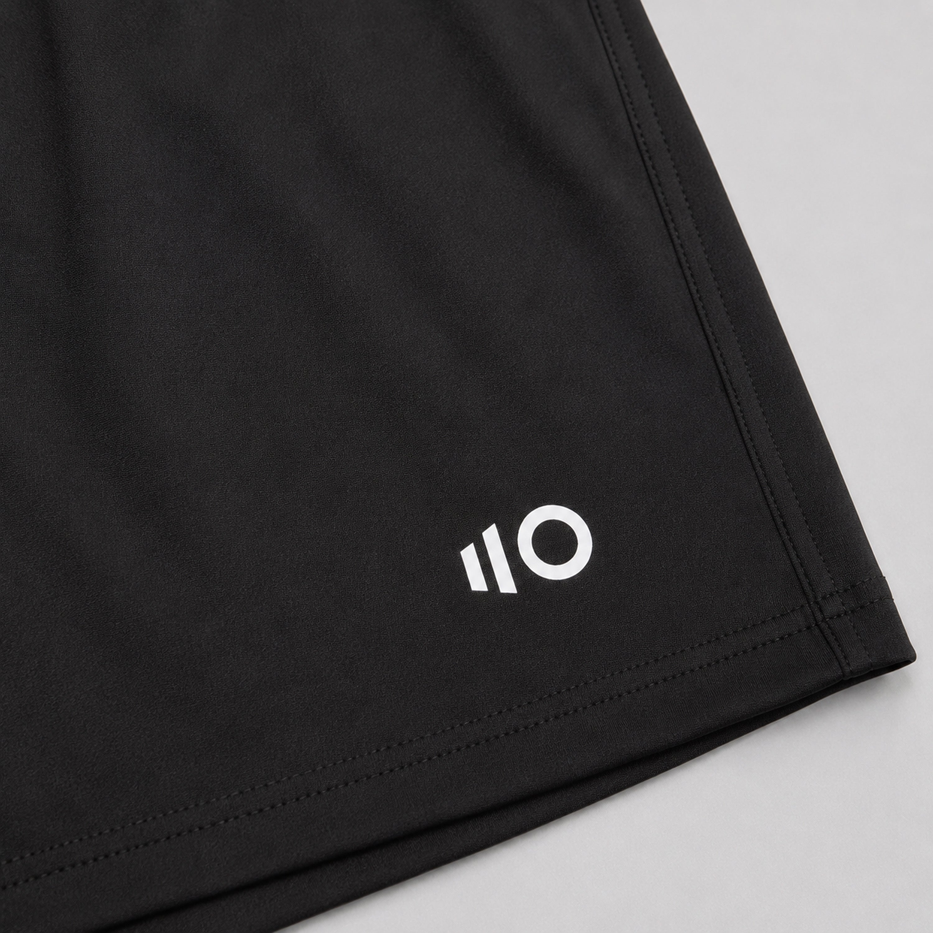 Black shorts with a white logo on a light gray background