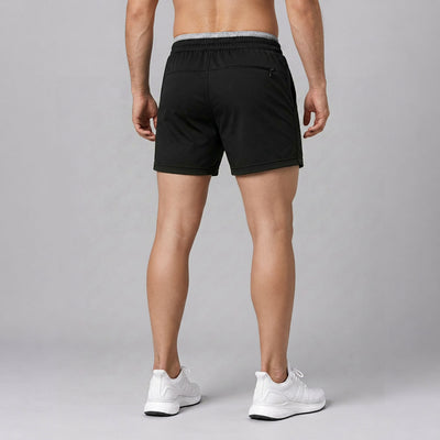 Person wearing black shorts and white sneakers on a gray background