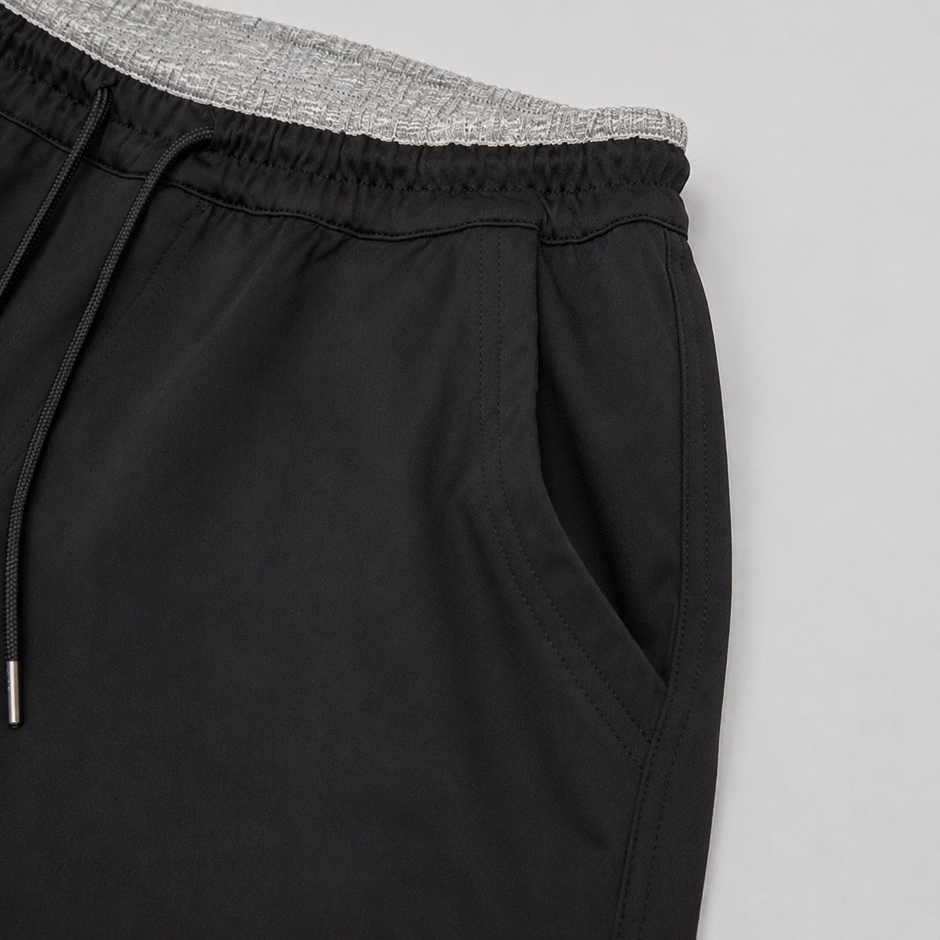 Black pants with a gray waistband on a light gray background