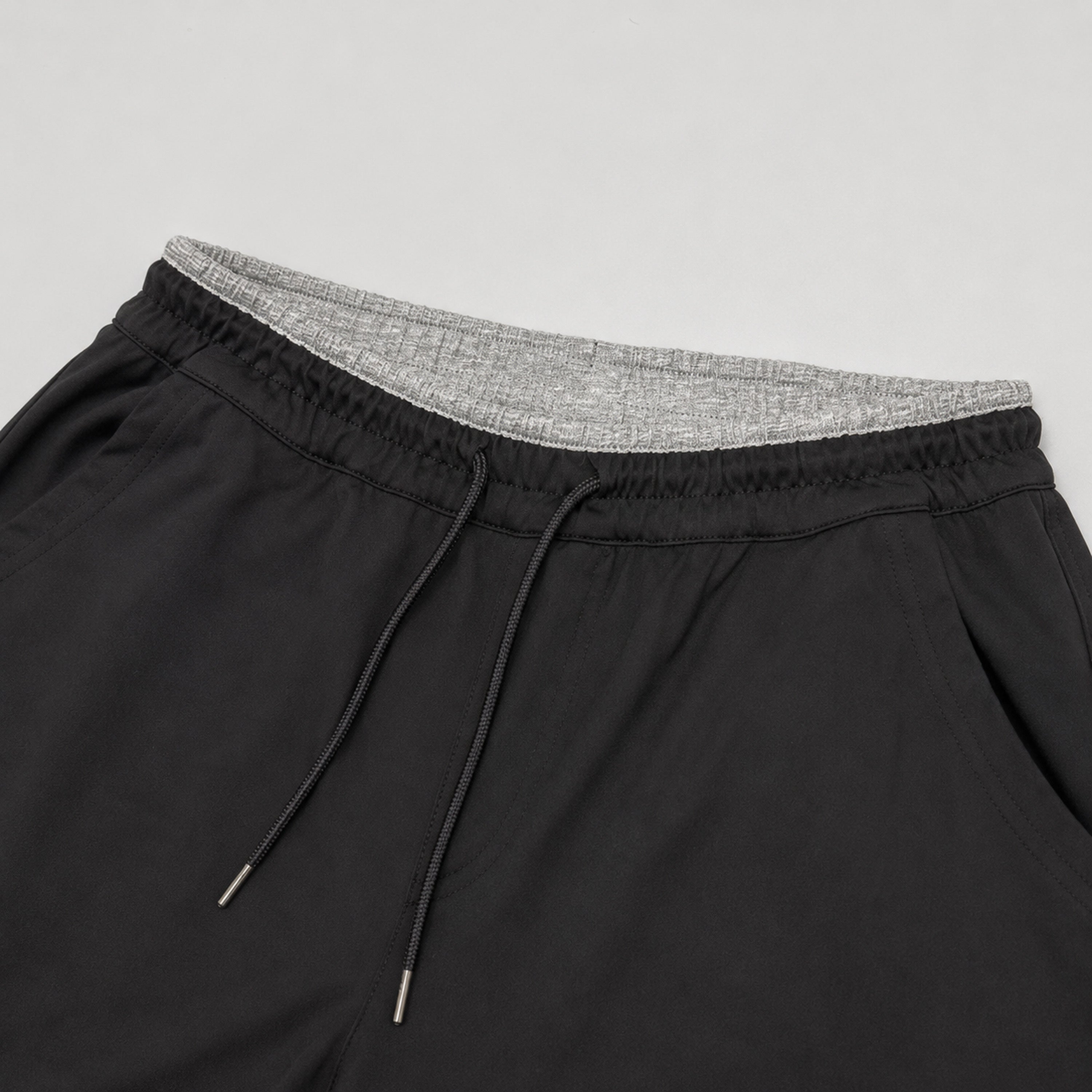 Black shorts with gray waistband on a light gray background