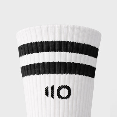 White sock with black stripes and logo on a light gray background