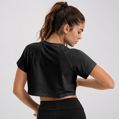 Woman wearing a black crop top against a plain background