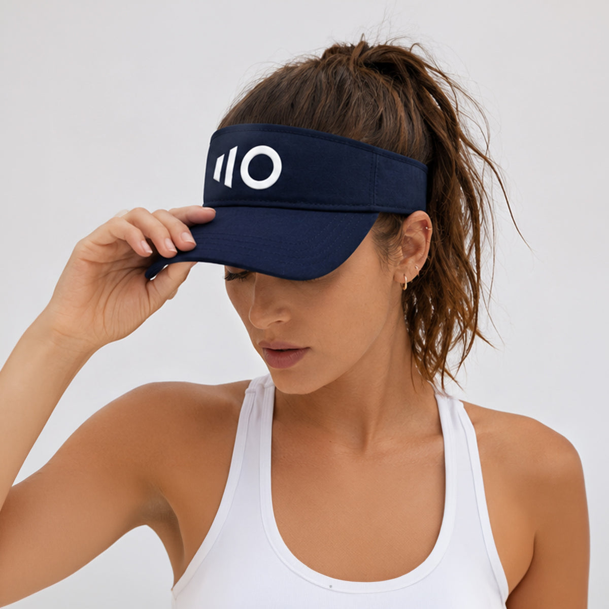 Woman wearing a navy visor with a logo on a plain background