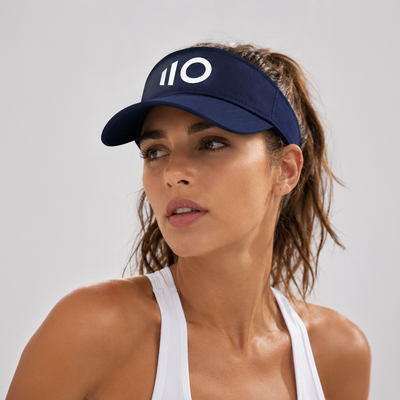 Woman wearing a navy visor with a logo on a gray background